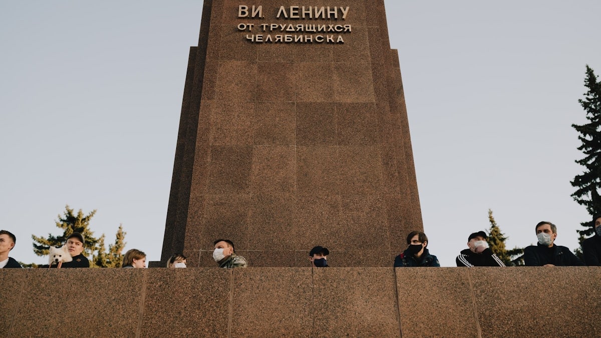 people sitting on brown concrete bench near gray concrete monument during daytime