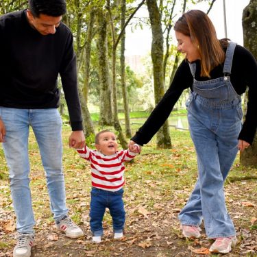 A joyful family enjoys a walk under lush green trees in the park.